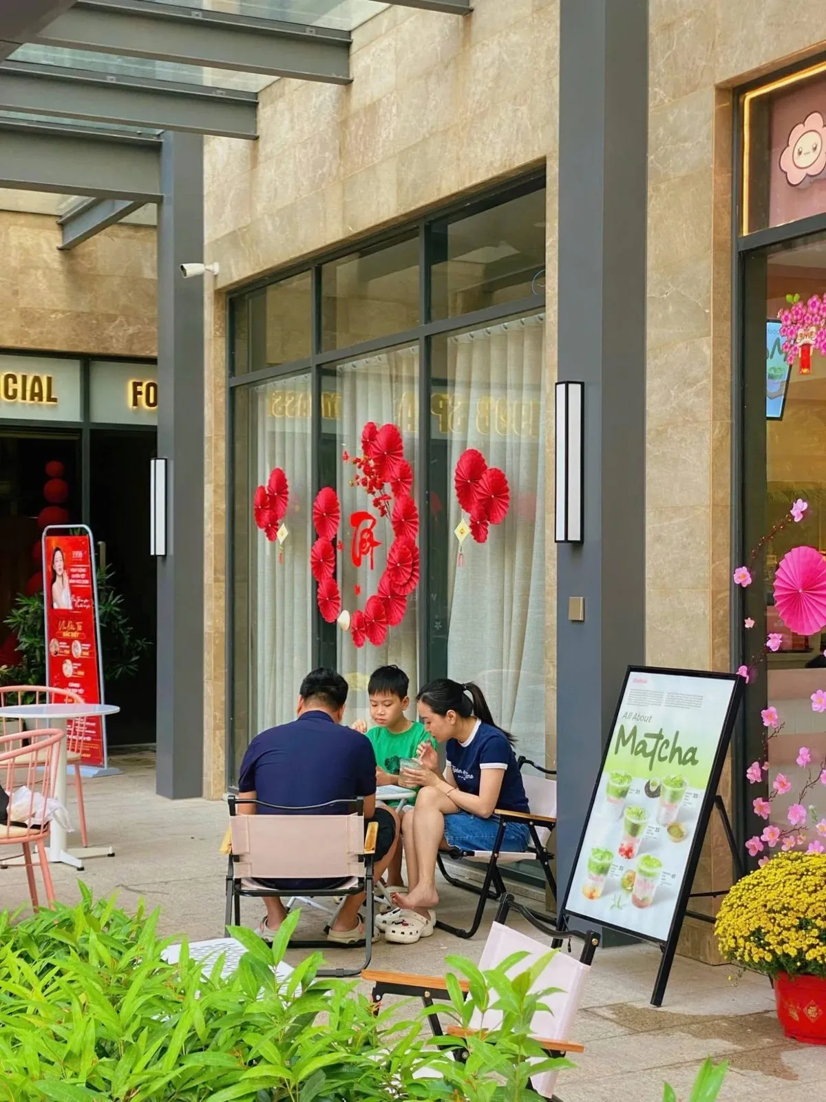 Gia đình ba người ngồi uống trà trước quán The Hoa Grand Park