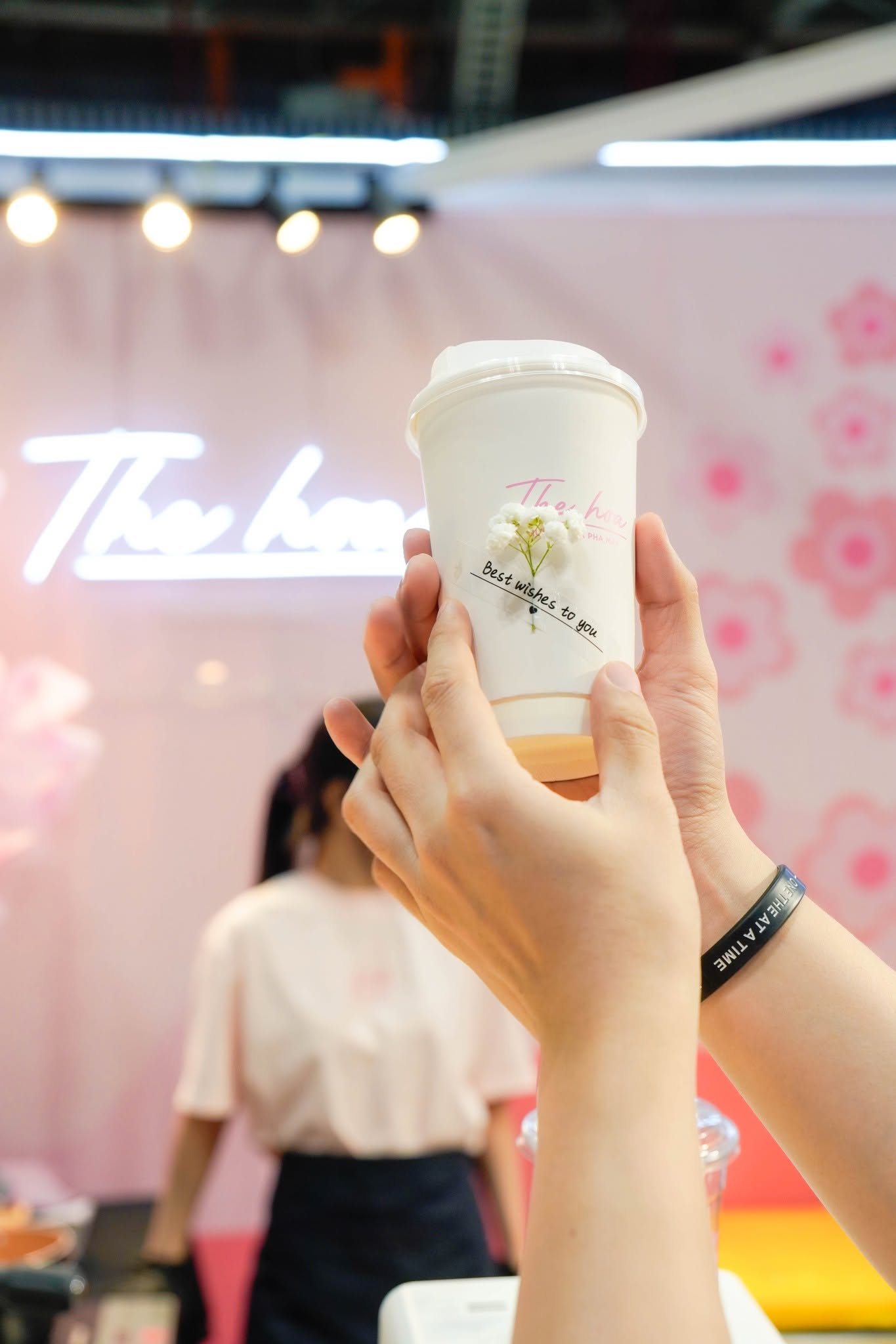 Ly trà The Hoa bên biển hiệu The Hoa